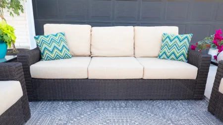 Outdoor seating area featuring a stylish sofa with decorative pillows on a patterned rug.