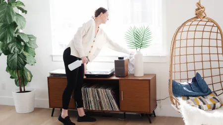 a person dusting a side table in a living room