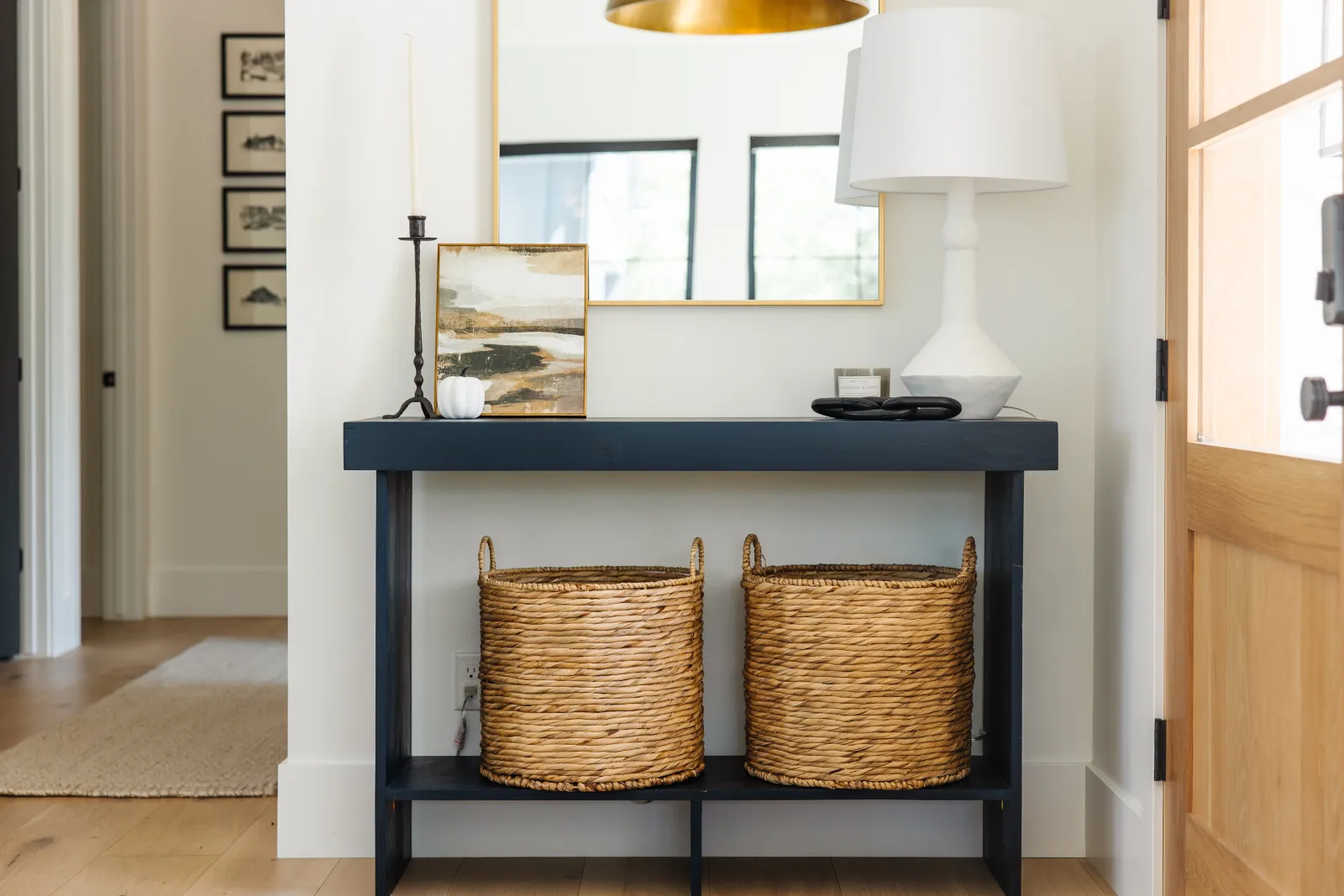 black side table by front door with wicker baskets