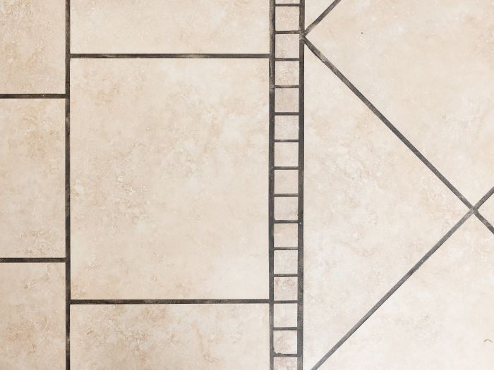 close up, top down view of a beige tile floor with dark dirty grout