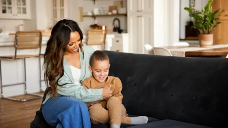Mother and son sitting on black couch in a cozy living room sharing a happy moment together